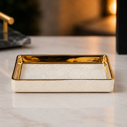 White ceramic soap dish with gold-coated inner walls and a dotted floor