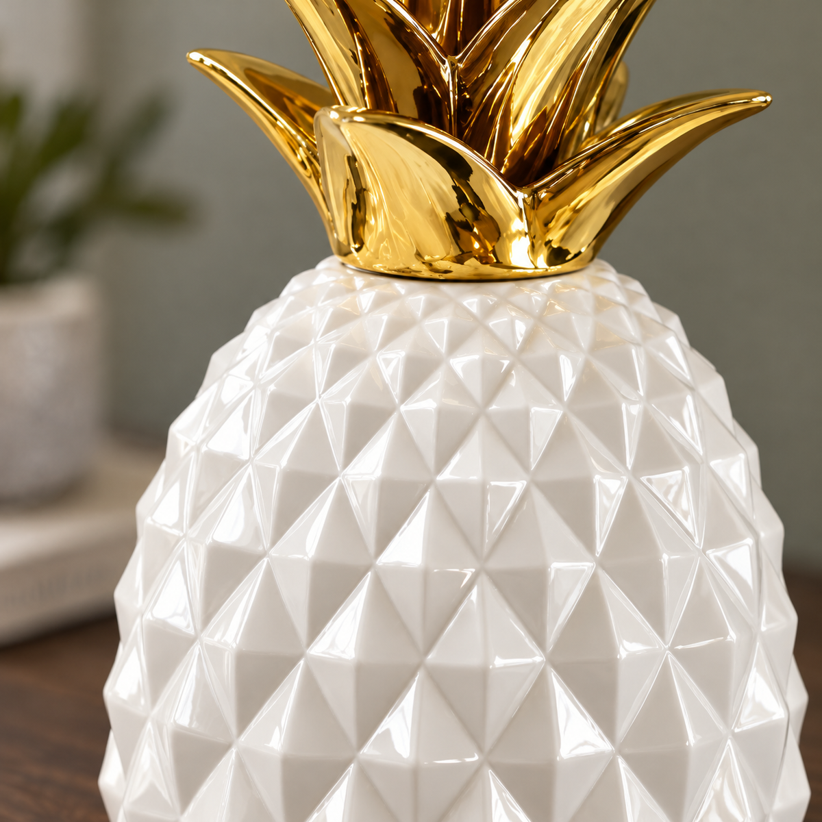 Close view of the glossy pyramid facets on the white pineapple sculpture, below the base of its gold crown