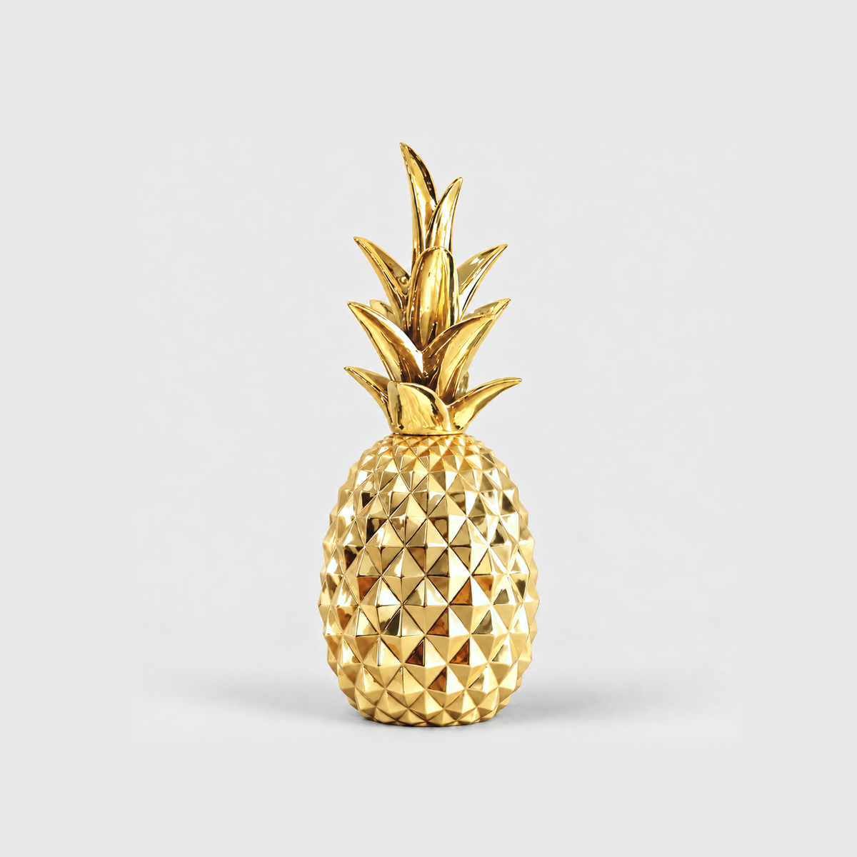 A mirror-gold resin pineapple sculpture with a faceted body, standing on a light gray background