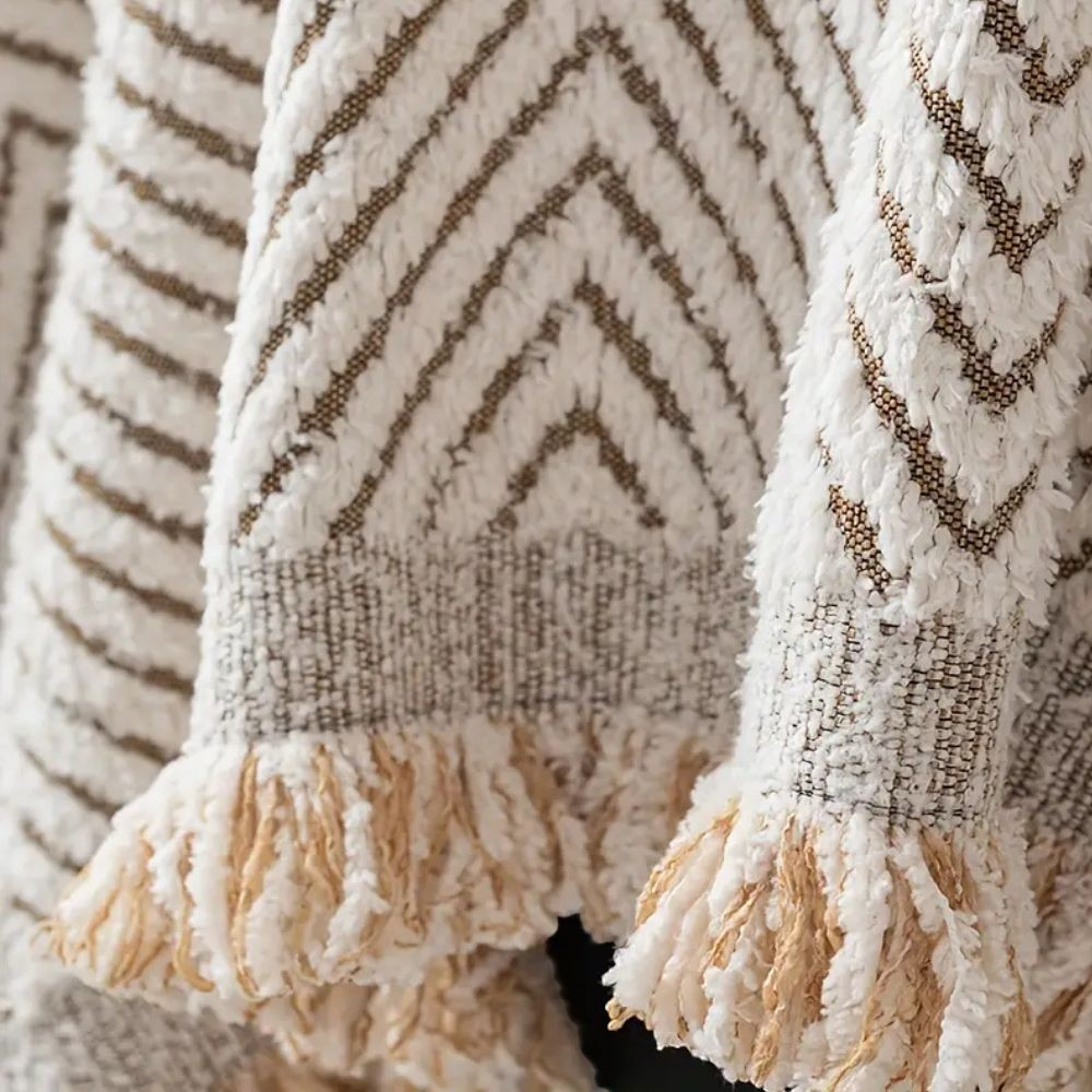 Close-up of the herringbone cover: soft raised pile, flat woven lines between the ridges, a woven band and a cut fringe