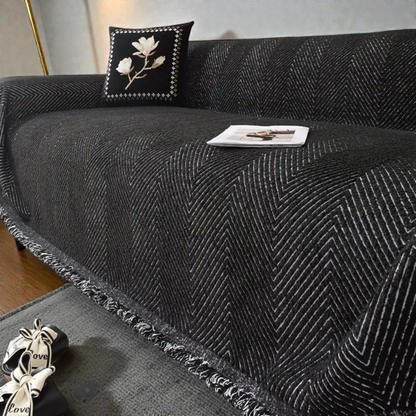 Black herringbone sofa cover with white V-shaped lines draped over a sofa, black and white fringe along the hem