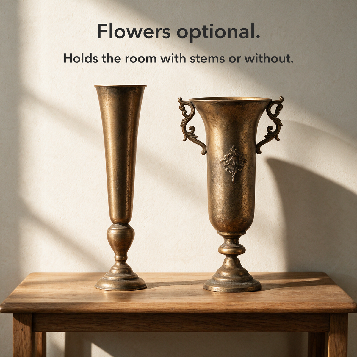 Text card reading Flowers optional over the Slim and Royal antique gold vases standing empty side by side on a wooden table