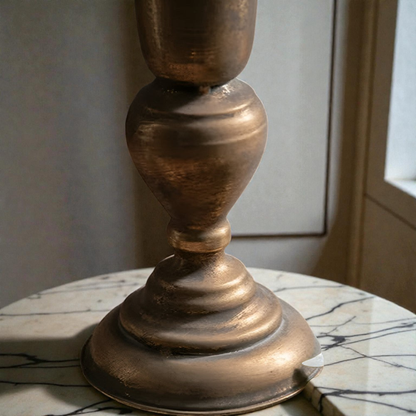 Close-up of the rounded knop and stepped foot under the antique gold trumpet vase
