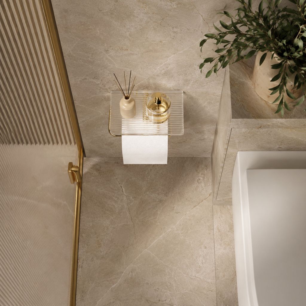 View from above of a marble bathroom with the gold toilet paper holder and its clear shelf on the wall