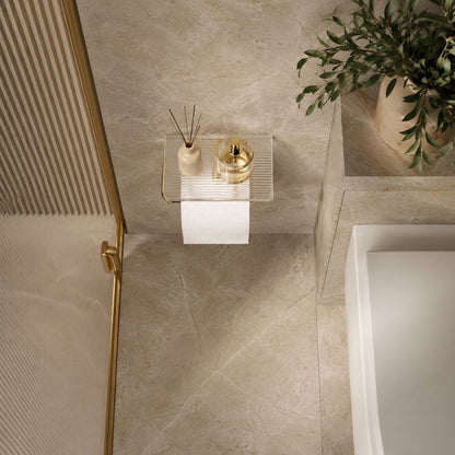 View from above of a marble bathroom with the gold toilet paper holder and its clear shelf on the wall