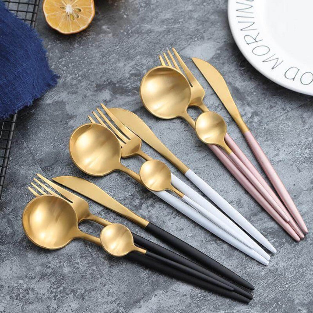 Black, white and pink gold flatware on a gray stone counter