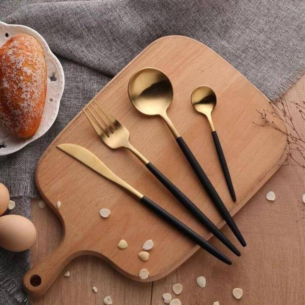 Black and gold knife, fork and spoons on a wooden board with bread