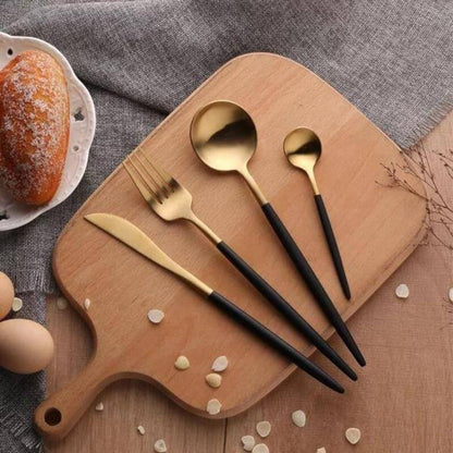 Black and gold knife, fork and spoons on a wooden board with bread