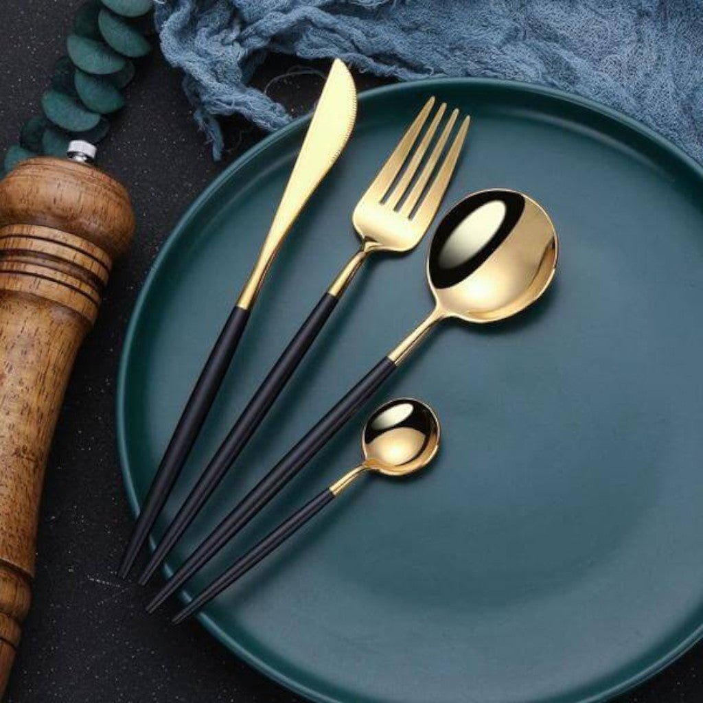Black and gold flatware on a dark teal plate