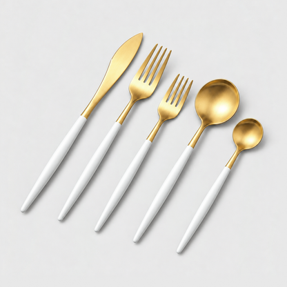 Gold flatware place setting with white handles on a light gray background
