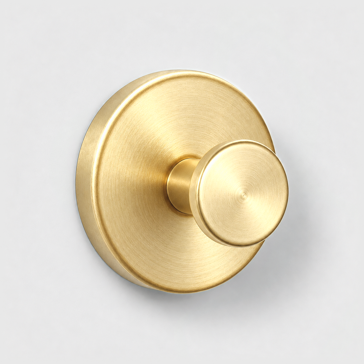 Brushed gold suction cup wall hook on a light gray wall