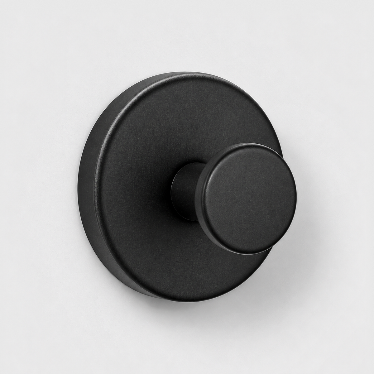 Black suction cup wall hook on a light gray wall
