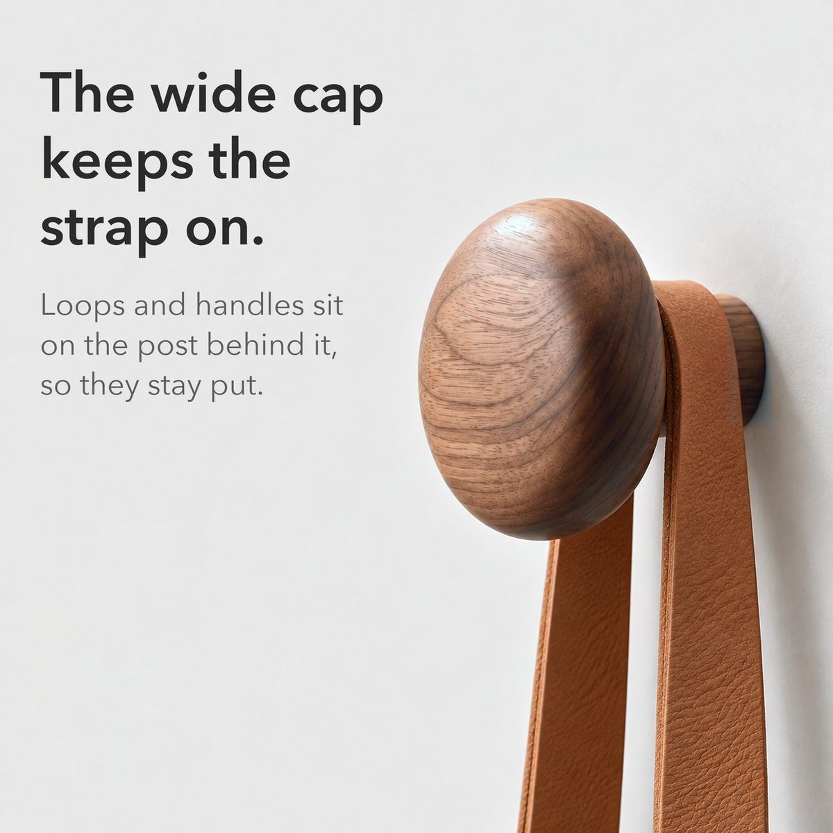 Leather strap resting on the post behind a round walnut hook cap, text reading the wide cap keeps the strap on