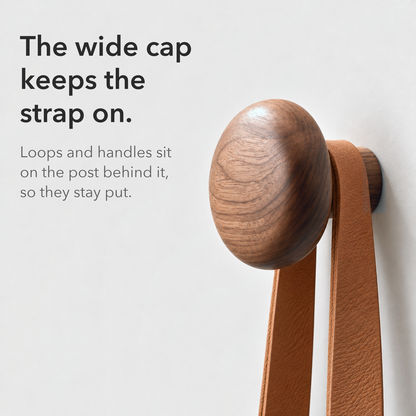 Leather strap resting on the post behind a round walnut hook cap, text reading the wide cap keeps the strap on
