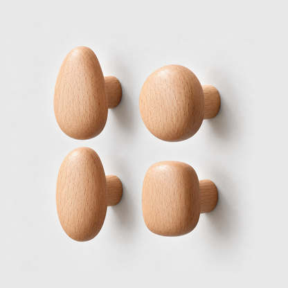 Set of four beech pebble wall hooks in teardrop, round, oval and rounded square shapes on a plain gray wall