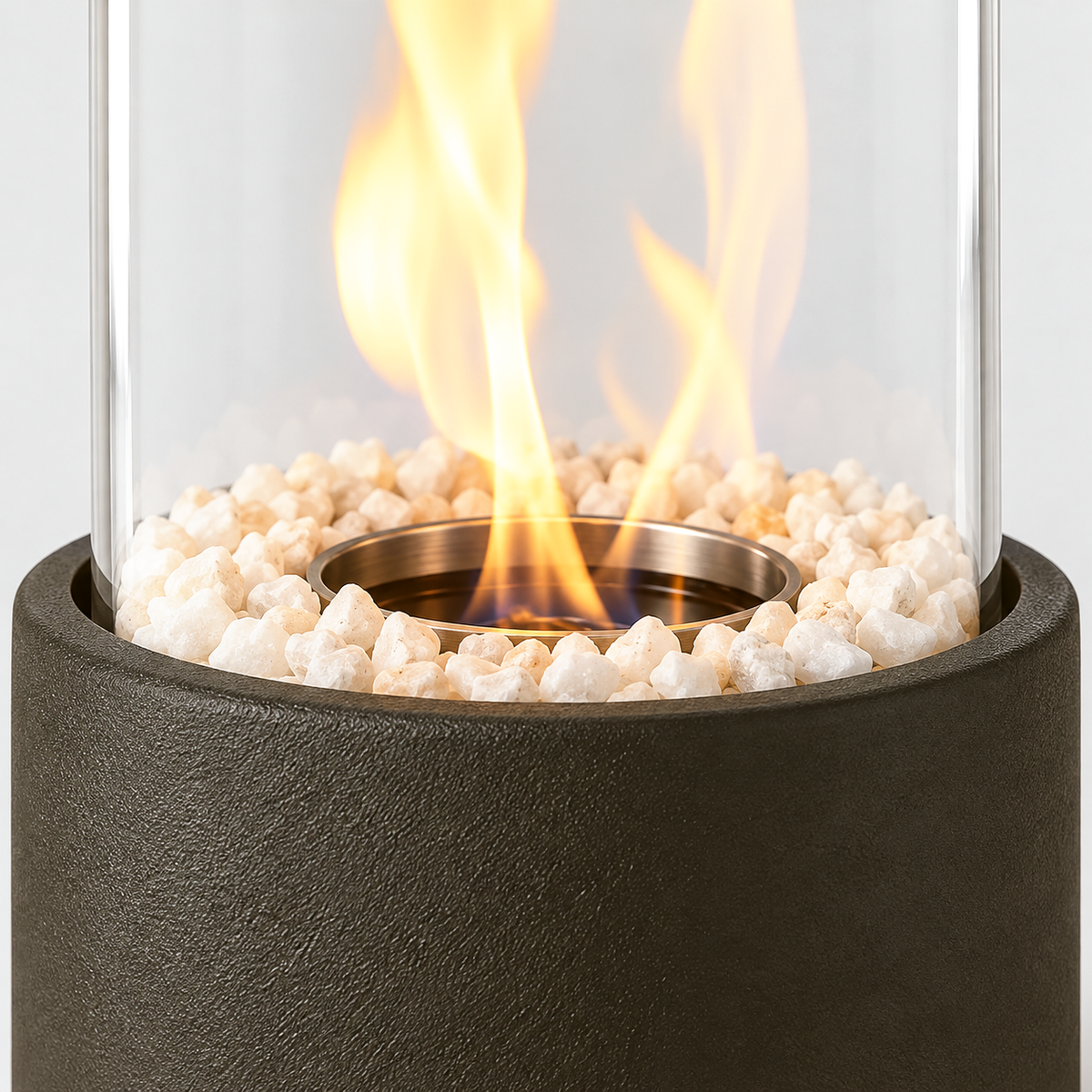 Close-up of the glass cylinder standing in the textured black base, with white stones and the flame rising from the central burner