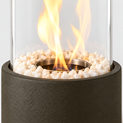 Close-up of the glass cylinder standing in the textured black base, with white stones and the flame rising from the central burner