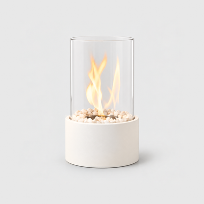 White glass cylinder tabletop fire pit with a lit flame inside the clear glass and a smooth matte base, on a light gray background