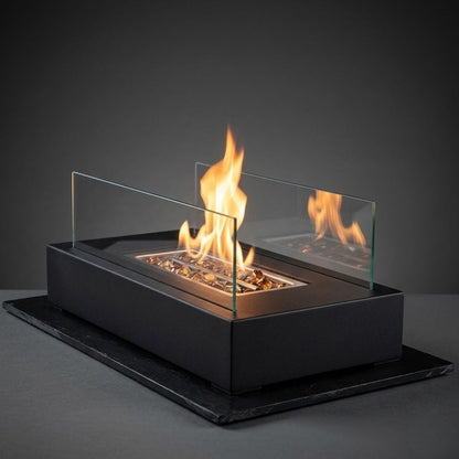 Lit tabletop fire pit standing on a black slate against a dark gray background