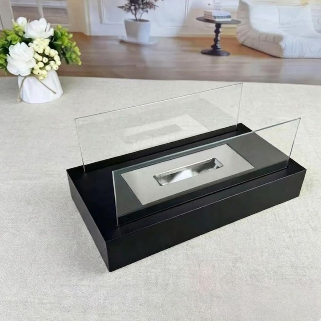 Unlit rectangle tabletop fire pit on a cream rug, showing its two glass panels and the steel burner in the black base