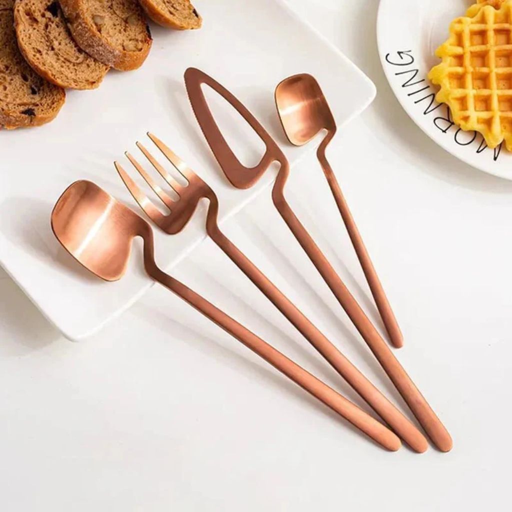 Rose gold flatware set on a white breakfast tray with toast