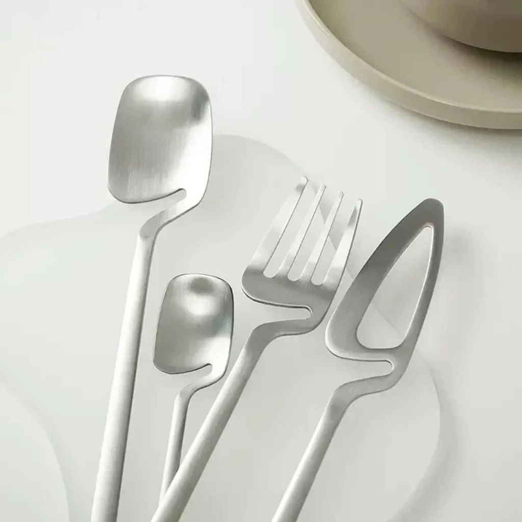 Close-up of the silver flatware spoon, teaspoon, fork and open-blade knife on a white plate