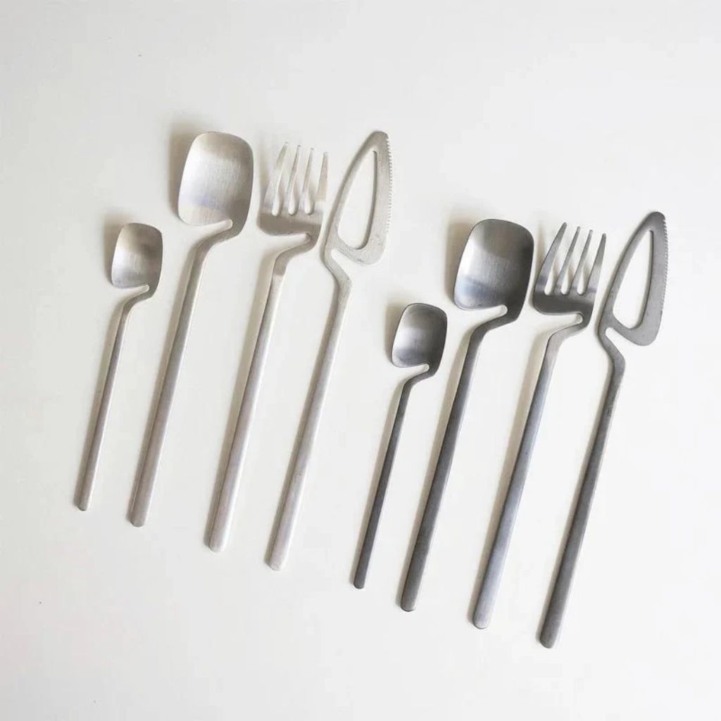 Two silver flatware sets with brushed satin finish on a pale gray surface