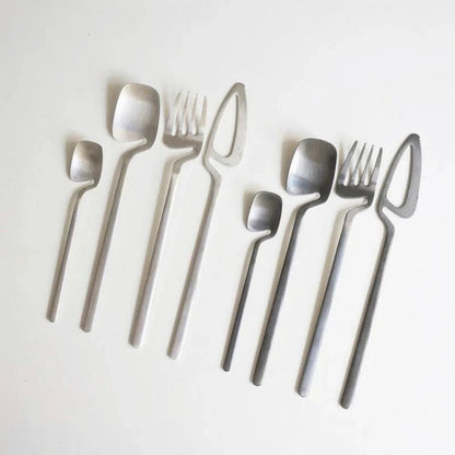 Two silver flatware sets with brushed satin finish on a pale gray surface
