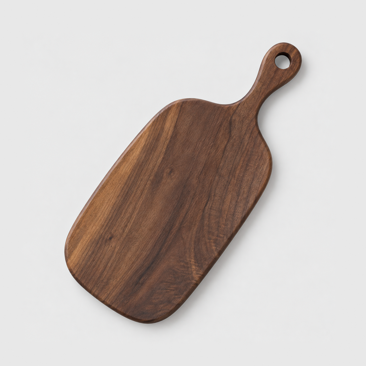 Black walnut paddle cutting board with a handle and hang hole, small size, on a light gray background