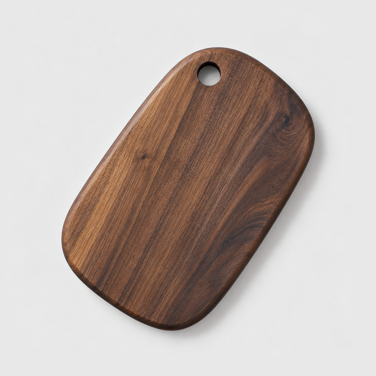 Small black walnut cutting board with a hang hole on a light gray background