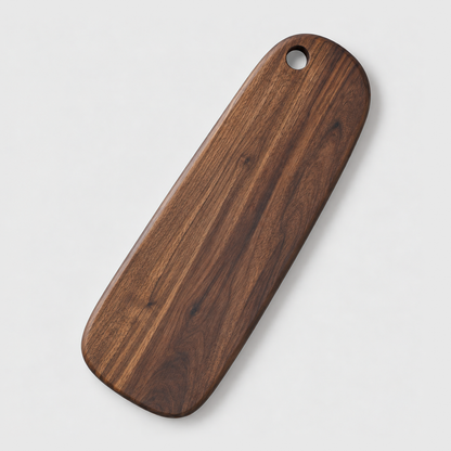 Long narrow black walnut cutting board with a hang hole on a light gray background