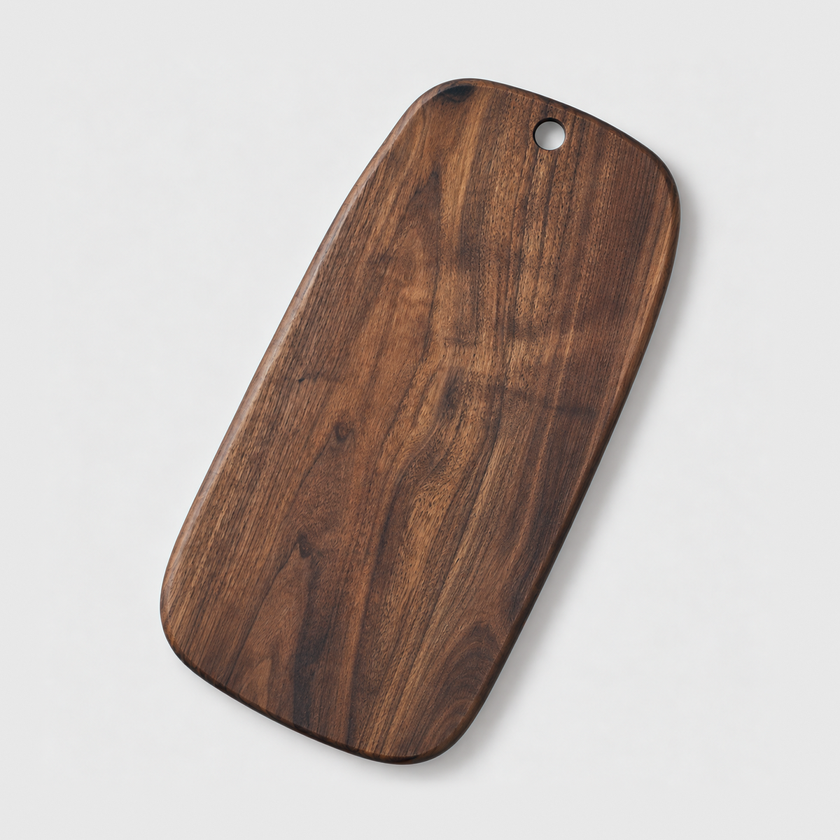 Large black walnut cutting board with a hang hole on a light gray background