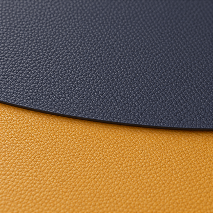 Close-up of the fine pebble grain and thin edge where a navy placemat overlaps a mustard one