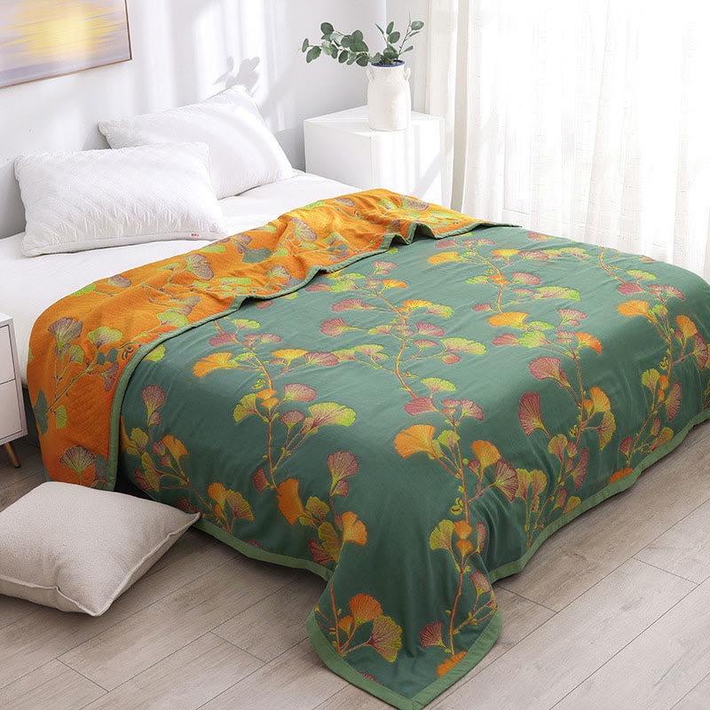 Ginkgo quilt over a bed with the top folded back, the sage-green face on the bed and the burnt orange reverse across the pillows