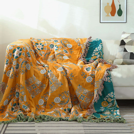 Mustard vintage floral throw draped over a white sofa, with its teal-green reverse showing down the right side