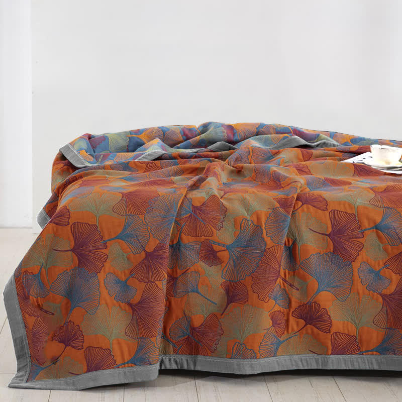 Blue and orange ginkgo leaf quilt over a bed, orange face up with the slate blue reverse turned back at the head