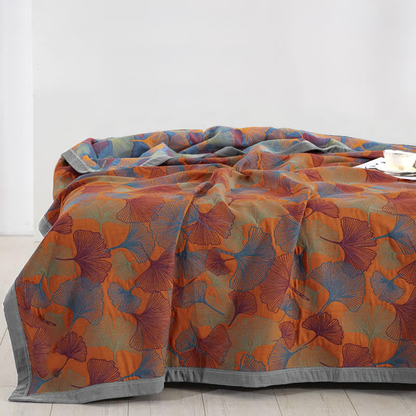 Blue and orange ginkgo leaf quilt over a bed, orange face up with the slate blue reverse turned back at the head