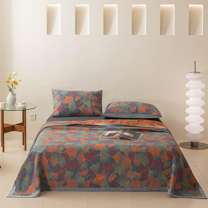 Bed made with the ginkgo leaf quilt and two matching pillowcases, beside a round glass side table