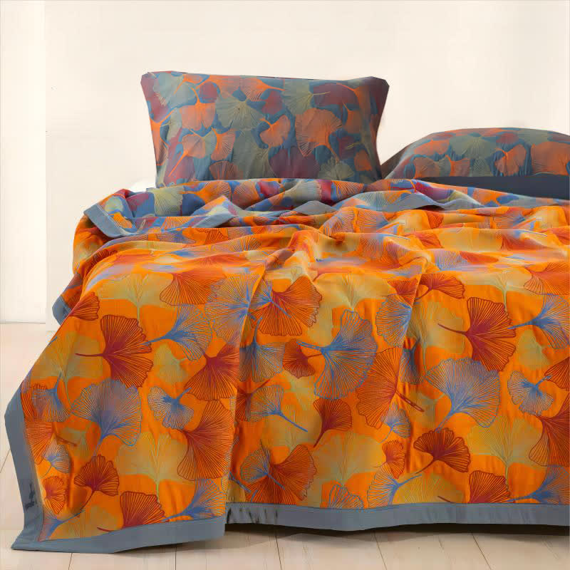 Orange ginkgo leaf quilt on a bed with two matching blue and orange pillowcases
