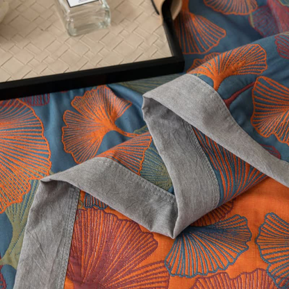 Close-up of a folded corner of the quilt: the wide gray stitched border with the blue face and the orange face either side