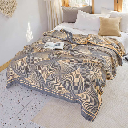 Yellow and charcoal tree ring cotton quilt spread over a bed, with its gray striped border band along the foot