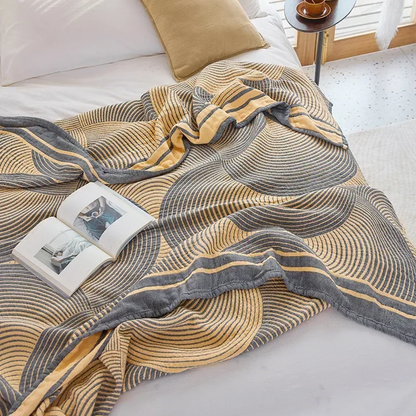 Yellow tree ring quilt draped over a bed, its edge turned back to show the solid yellow reverse of the striped border