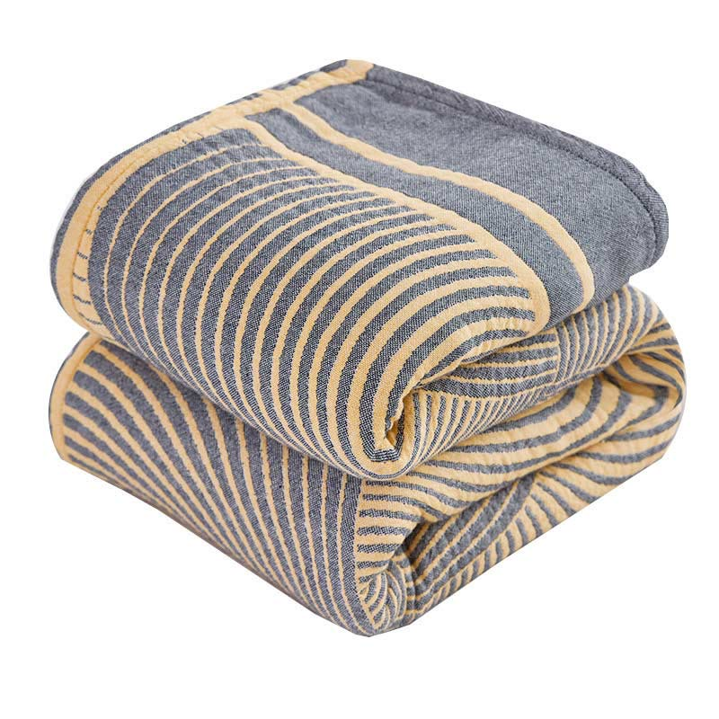 Gray and yellow tree ring cotton quilt folded on a white background, showing the woven rings and border band