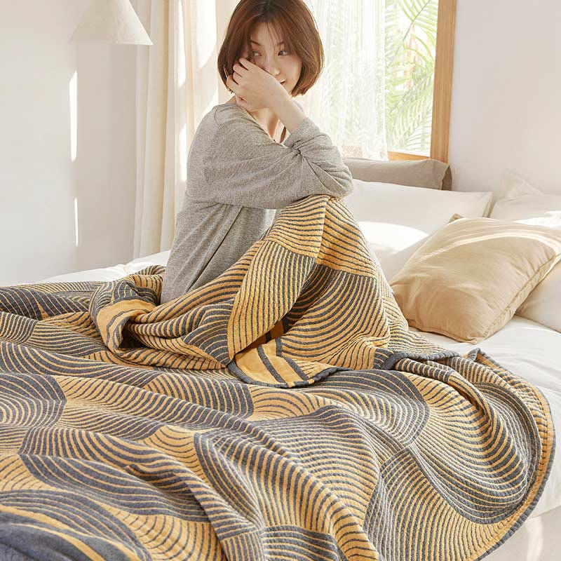 Yellow tree ring quilt gathered over the knees of someone sitting up in a sunny bedroom