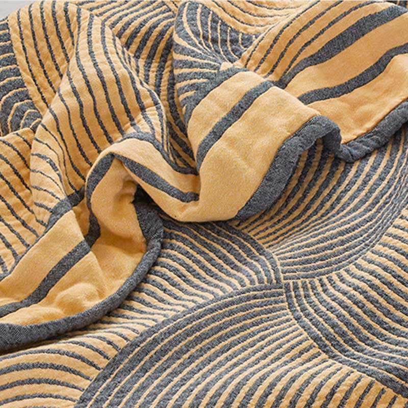 Close-up of the cotton gauze quilt folded over, showing woven rings and the border band in gray on one side and yellow on the other