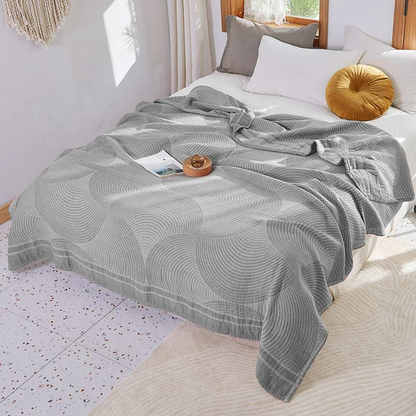 Gray tree ring cotton quilt in pale and mid gray spread over a bed, with a gray border band along the foot