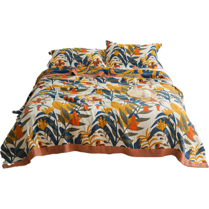 Goldenrod floral cotton quilt spread over a bed, mustard, blue and olive leaves on cream with a terracotta border
