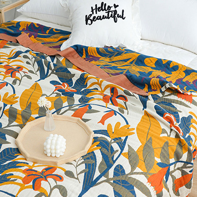 Cream floral face of the cotton quilt on a bed with the navy reverse folded back at the pillows and the terracotta border between