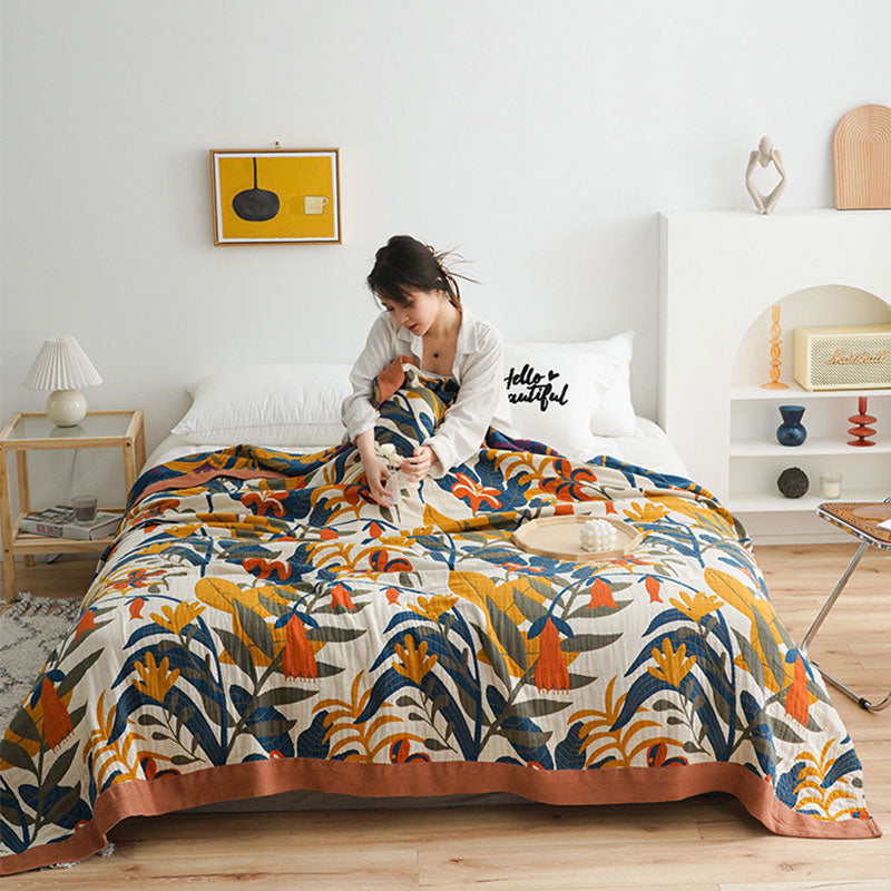 Floral cotton quilt covering a bed in a white bedroom, the terracotta border running along the foot