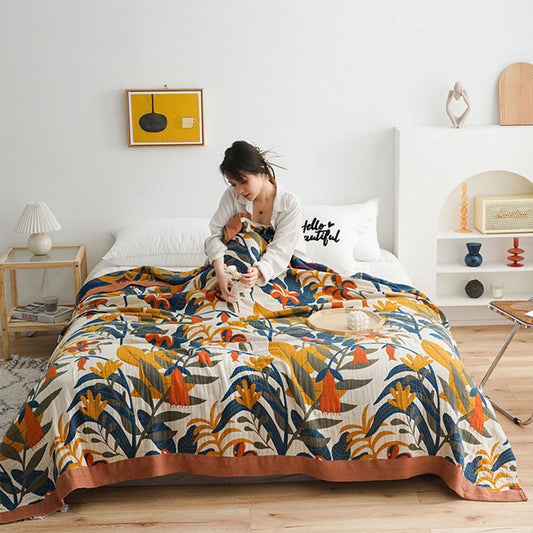 Floral cotton quilt covering a bed in a white bedroom, the terracotta border running along the foot